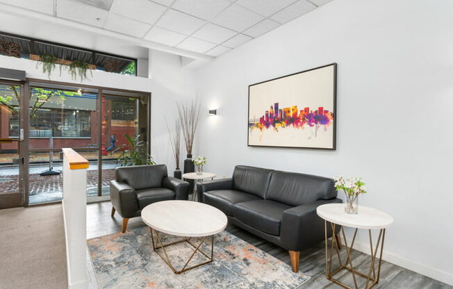 A black leather couch sits in a room with a large picture frame on the wall.at Fifth Avenue Place Apartments, Portland