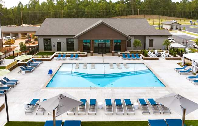 an aerial view of a pool with lounge chairs and a building