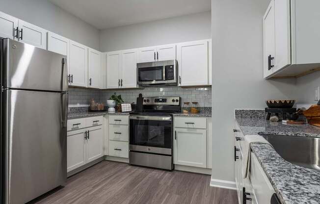 A kitchen with white cabinets and a stainless steel refrigerator.