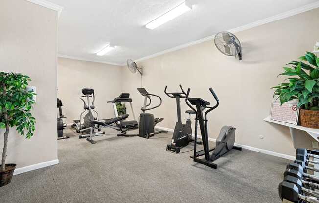 A room with exercise equipment and a fan on the wall.
