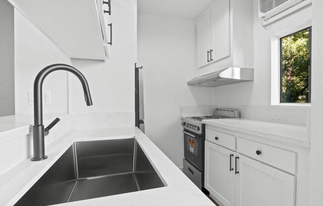 a kitchen with white cabinets and a black sink