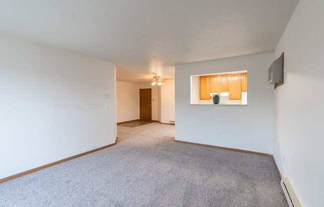 the living room and dining room of an apartment with white walls and carpet. Fargo, ND Oxford Apartments