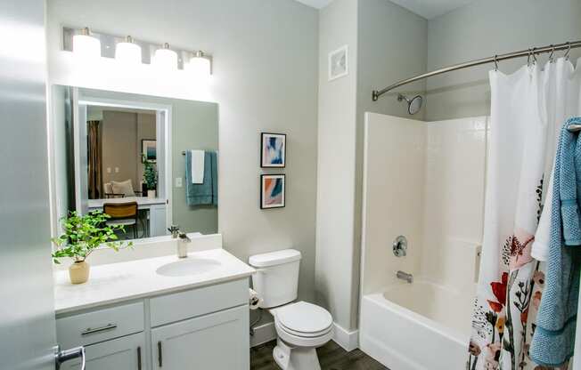 Octave Apartments  a bathroom with a white sink and toilet next to a white bathtub with a shower curtain at Octave Apartments, Las Vegas, Nevada