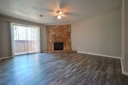 A room with a stone fireplace and wood flooring.