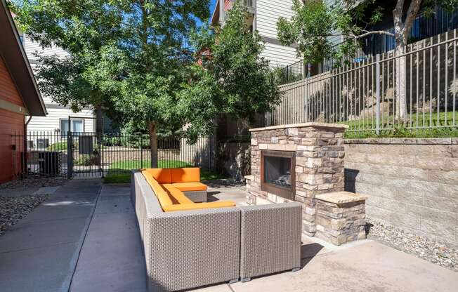 a patio with a fireplace and a couch in front of a fence at Stetson Meadows Apartments, Colorado Springs, CO, 80922