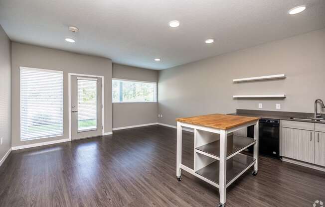 an empty living room with a table and a kitchen