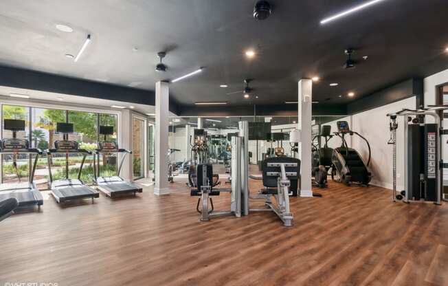 a gym with cardio machines and weights on a wooden floor