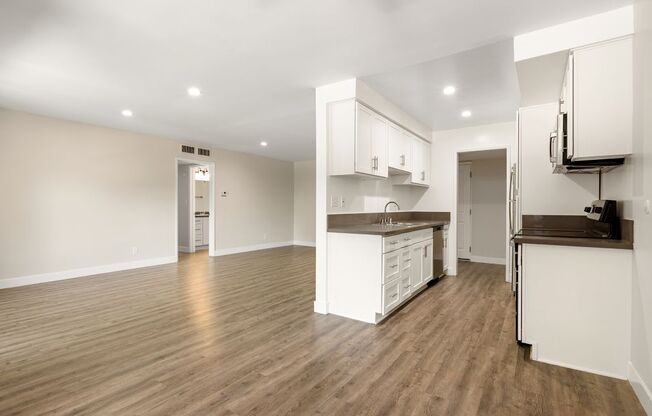 an empty living room and kitchen with a wood floor