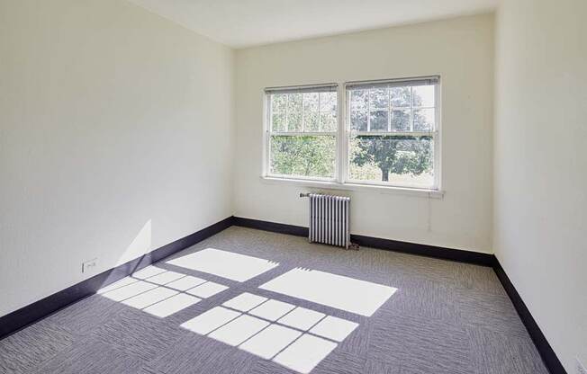 empty room with a large window and a radiator at MILEPOST 5 Apartments, PORTLAND, OR