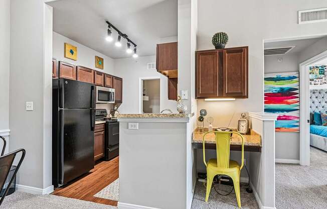 A kitchen with a black fridge and a yellow chair.