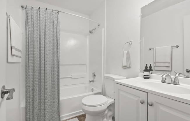 a white bathroom with a shower toilet and sink