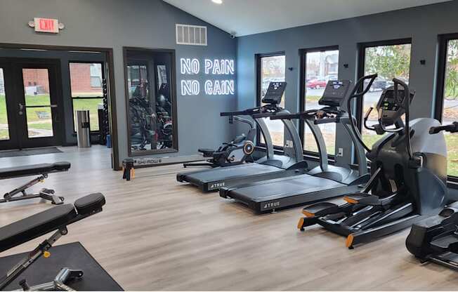 A gym with a variety of equipment including treadmills, weights, and exercise machines.