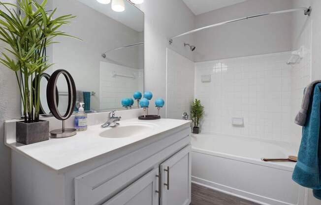 A white bathroom with a white sink and a white bathtub.