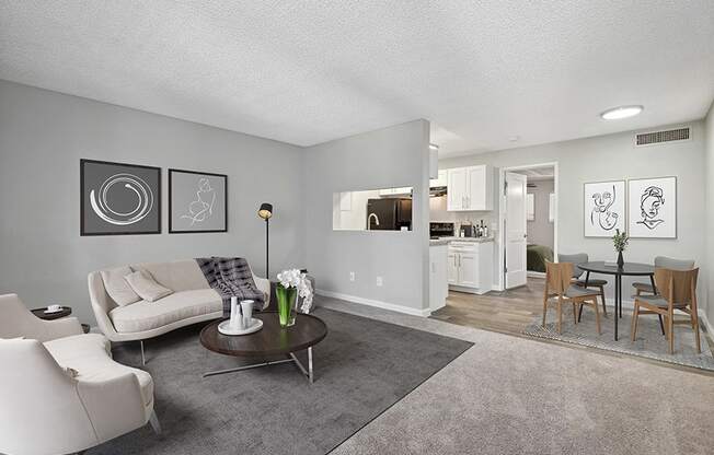 Model Living Room with Carpet and View of Kitchen/Dining Area at Stillwater Apartments in Glendale, AZ.