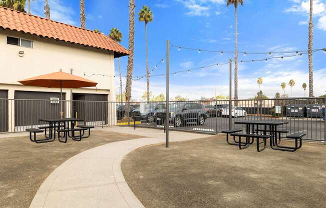 A patio area with picnic tables and a red umbrella.