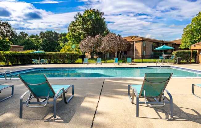 Heated pool equipped with comfy lounge chairs at Westwood Village Apartments in Westland, MI