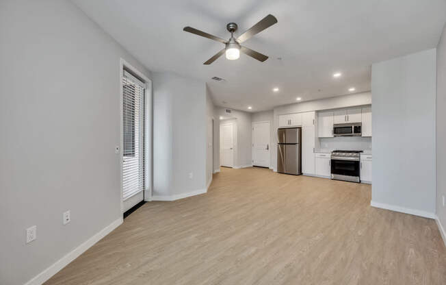 A spacious living room with a ceiling fan and hardwood flooring.