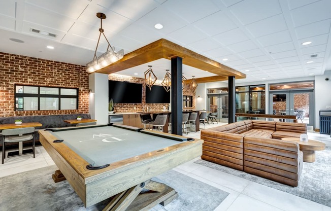 a pool table in a clubhouse with a bar and tables