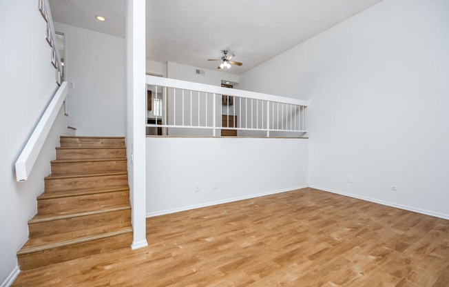 an empty living room with a hard wood floor and stairs