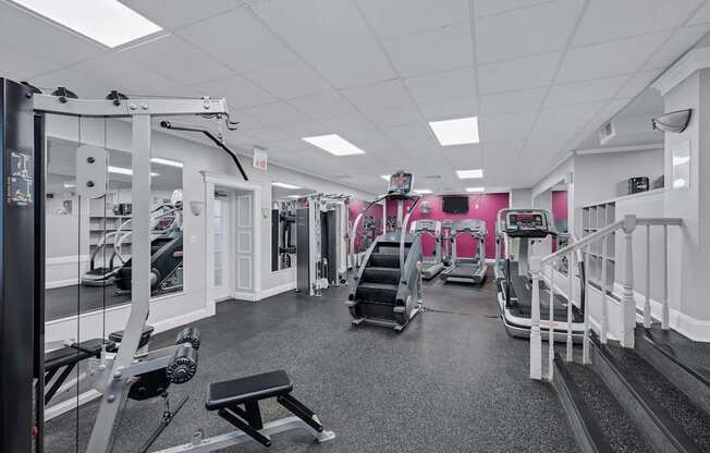 A gym with a variety of equipment including treadmills, weights, and exercise machines.