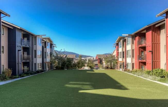 A sunny day at a residential area with apartment buildings and a green lawn.