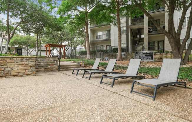 Pool loungers in the pool area with apartment buildings in the background at Jefferson Place apartments in Irving, TX