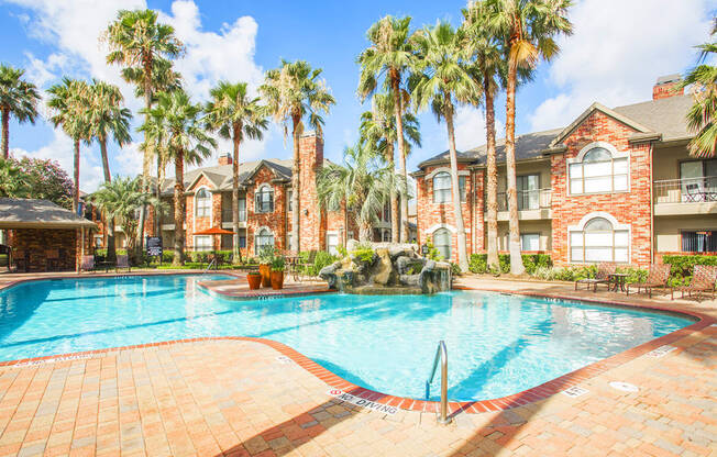 a large swimming pool in front of a building with palm trees