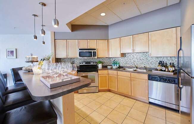 A kitchen with a bar, chairs and a microwave above the stove.
