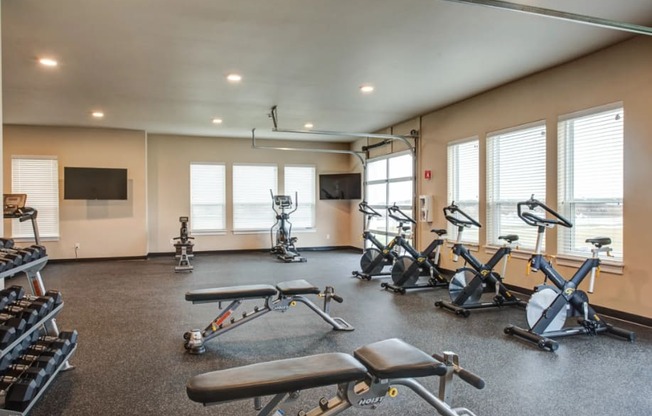the gym has plenty of exercise equipment and windows