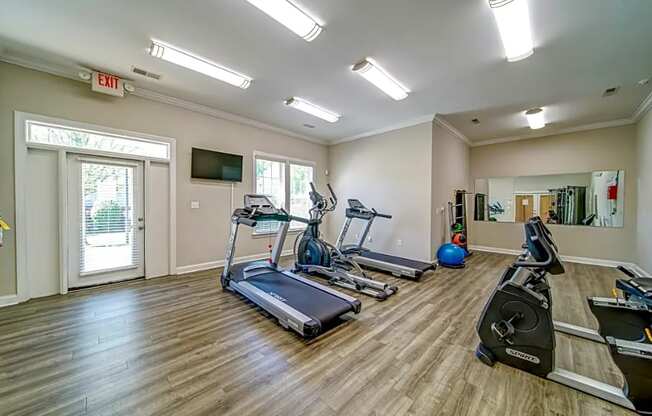 a gym with treadmills and weights and a tv