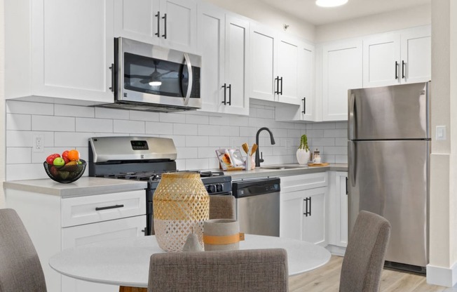 a kitchen with white cabinets and stainless steel appliances