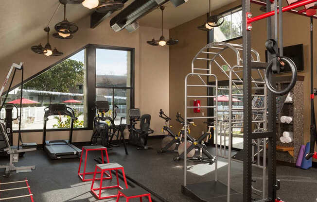 A gym with a variety of equipment including a treadmill, weights, and a pull up bar.