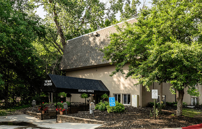 a building with a black awning and trees in front of it