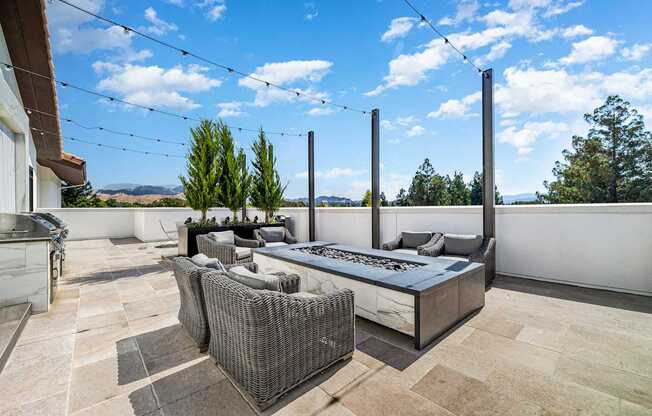 Rooftop terrace with lounge seating, outdoor firepit, and views of rolling hills