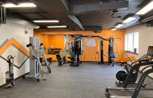 a gym with a row of exercise machines and a pattern on the wall at Troy Place Apartments - Troy, MI, Troy, 48084