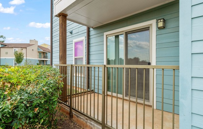A blue house with a white door and a window with a pink curtain.