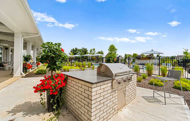 A brick BBQ is in a concrete patio in front of a house.