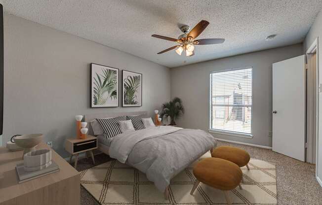 A bedroom with a bed, two chairs, and a ceiling fan.