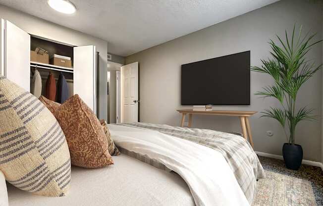 A bedroom with a bed, a television, and a plant.