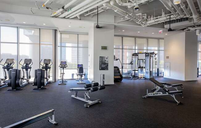 A gym with a variety of equipment including treadmills, weights, and exercise machines.