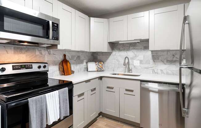 A kitchen with white cabinets and a black stove top oven. at Mill House at East Cobb, Georgia