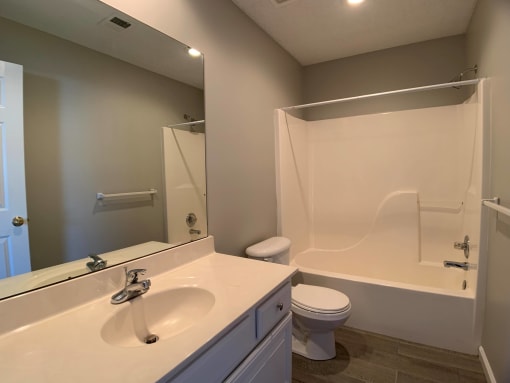 Hallway bath with large vanity, toilet, and full tub