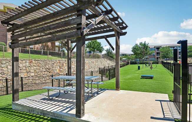 A wooden pergola is over a picnic table.