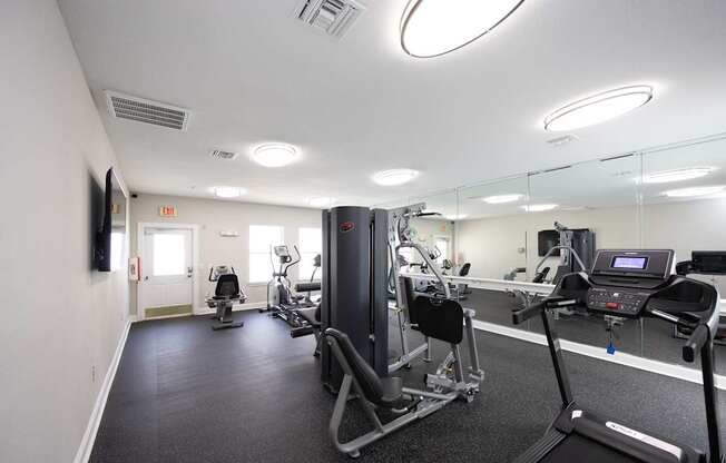 a gym with exercise equipment and mirrors in a building at Magnolia Pointe Apartments in Duluth, GA