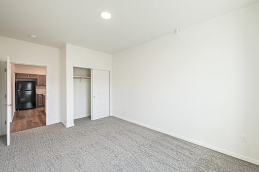 a living room with white walls and carpet and a door to a kitchen at Gateway Apartments, East Wenatchee 