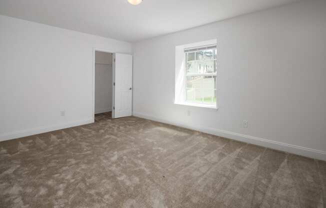 an empty living room with carpet and a window