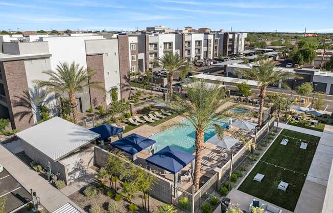 A pool surrounded by palm trees and a building in the background.