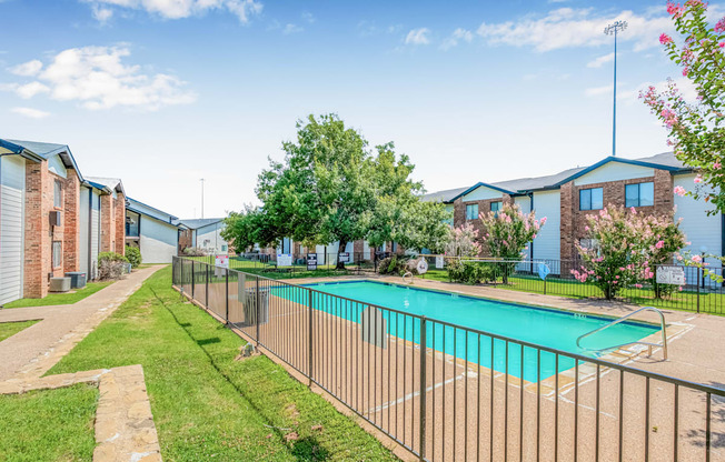 A pool surrounded by a fence in a sunny day.
