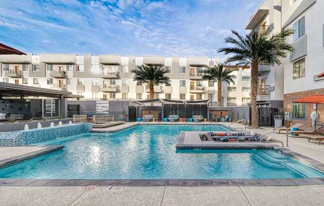 A large swimming pool in front of apartment buildings.