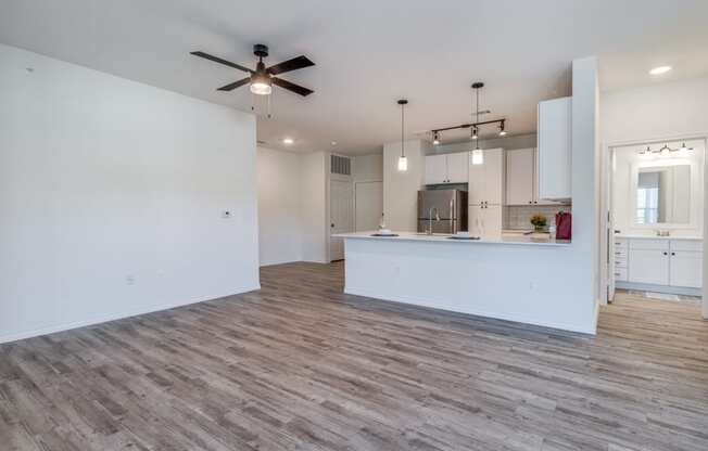 an empty living room and kitchen with a ceiling fan